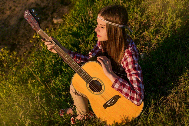 Girl playing an acoustic guitar in the grass